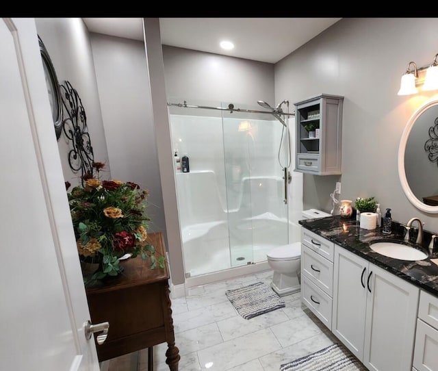 bathroom featuring toilet, a shower with shower door, and vanity