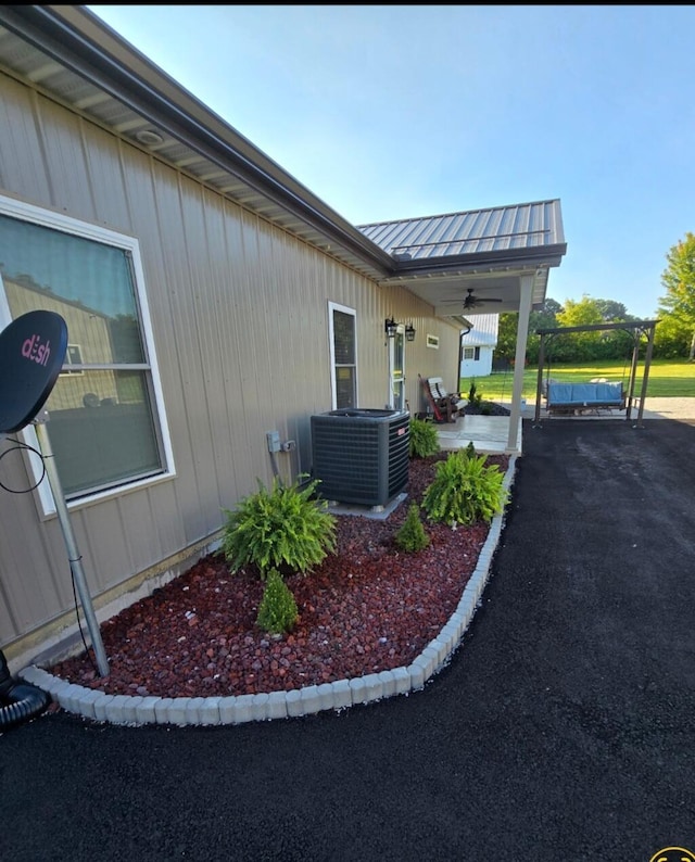 view of side of property featuring ceiling fan, a patio, central AC, and a carport