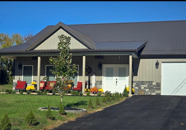 view of front of property featuring a garage, a porch, and a front yard