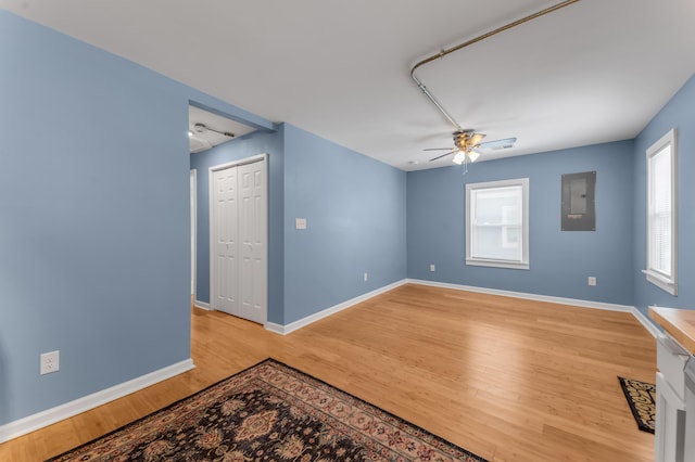 empty room with electric panel, a healthy amount of sunlight, ceiling fan, and wood-type flooring