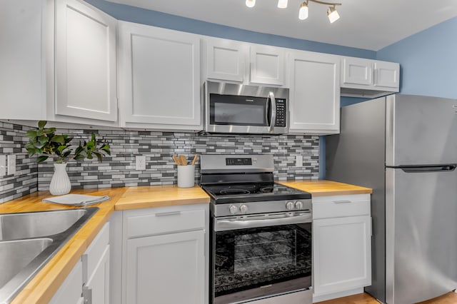 kitchen featuring backsplash, white cabinetry, wooden counters, and stainless steel appliances