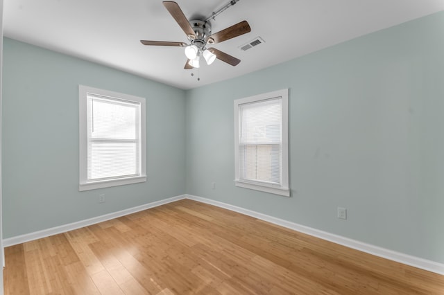 empty room featuring hardwood / wood-style floors, a wealth of natural light, and ceiling fan