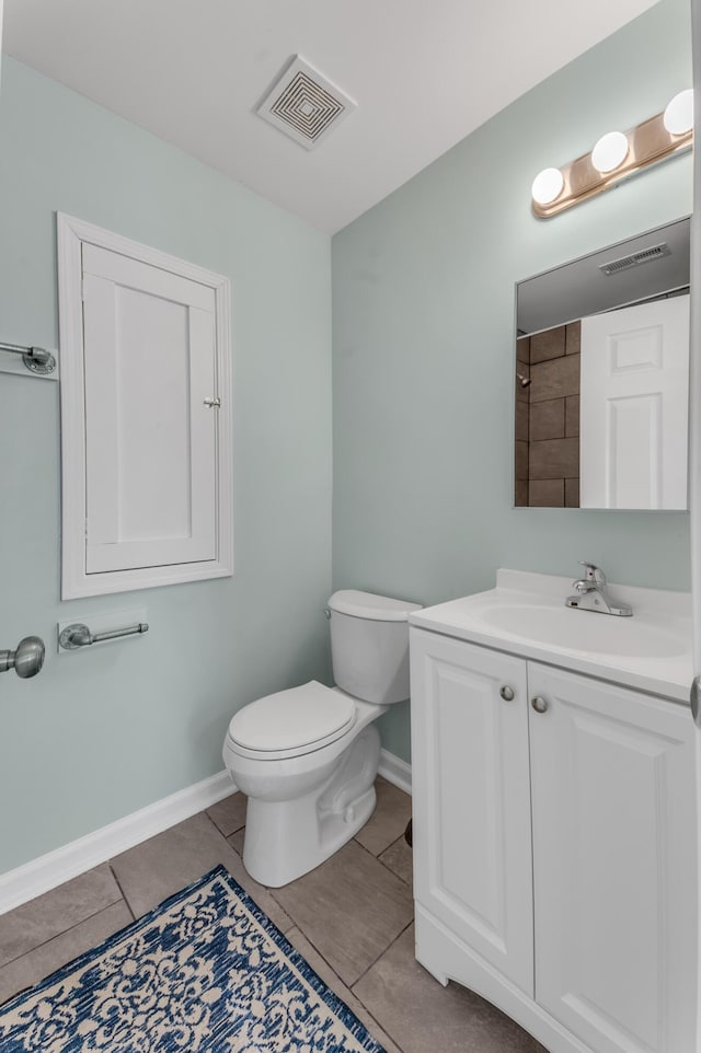 bathroom with toilet, vanity, and tile patterned floors