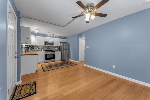 kitchen with white cabinetry, sink, stainless steel appliances, butcher block countertops, and decorative backsplash