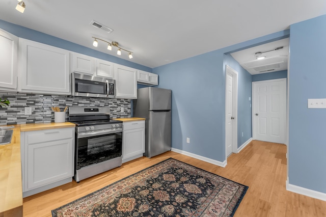 kitchen featuring appliances with stainless steel finishes, butcher block countertops, and white cabinetry