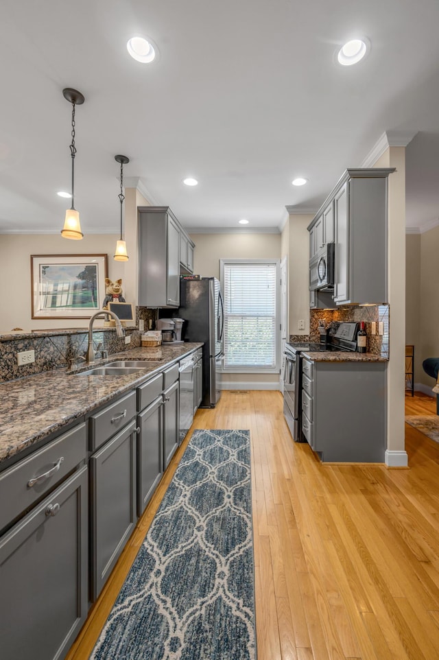 kitchen with appliances with stainless steel finishes, gray cabinetry, crown molding, light hardwood / wood-style floors, and hanging light fixtures