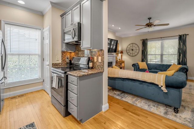 kitchen with gray cabinetry, light hardwood / wood-style flooring, ceiling fan, appliances with stainless steel finishes, and tasteful backsplash