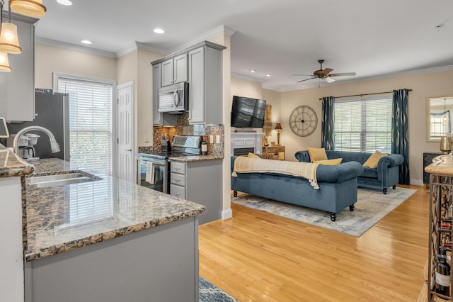 kitchen featuring appliances with stainless steel finishes, light hardwood / wood-style floors, hanging light fixtures, and sink