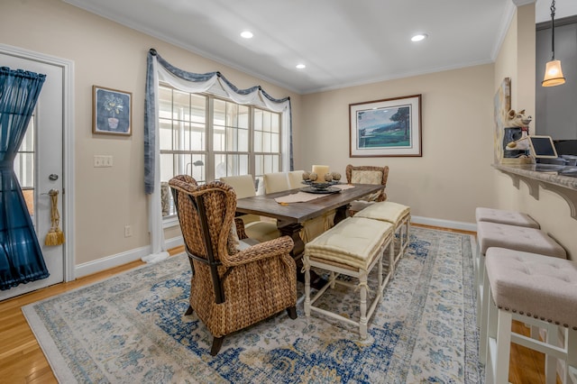 dining room with crown molding and light hardwood / wood-style flooring