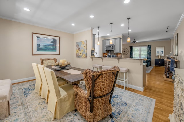 dining space with ceiling fan, light wood-type flooring, and ornamental molding