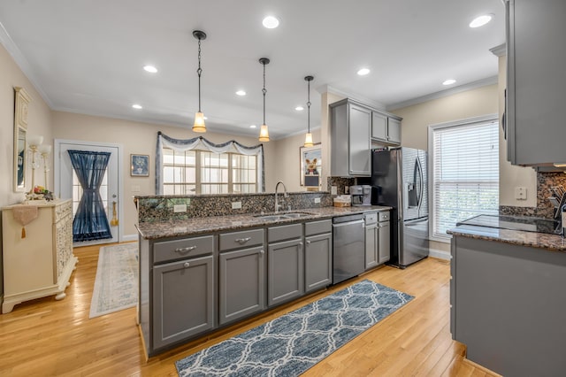 kitchen featuring gray cabinetry, sink, hanging light fixtures, light hardwood / wood-style floors, and stainless steel appliances