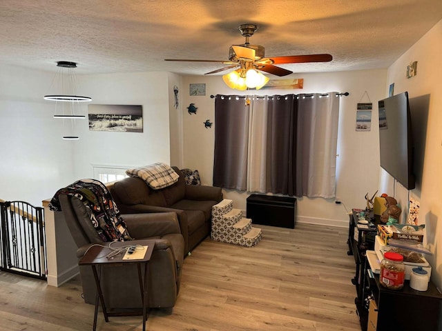 living room featuring ceiling fan, light hardwood / wood-style floors, and a textured ceiling