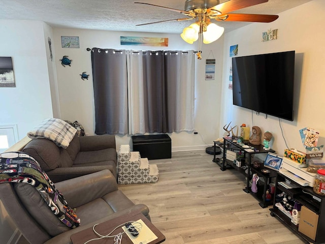 living room featuring ceiling fan, light hardwood / wood-style flooring, and a textured ceiling