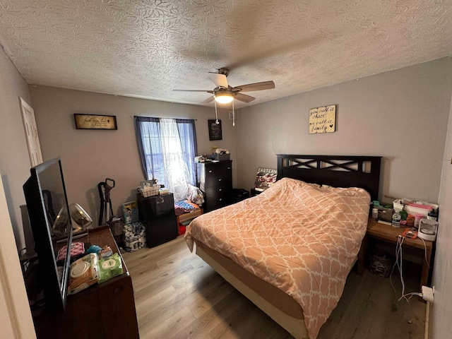 bedroom featuring ceiling fan, a textured ceiling, and light wood-type flooring