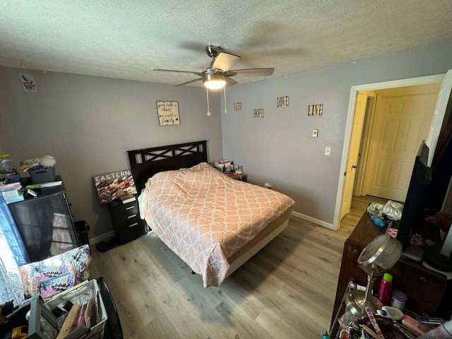 bedroom with ceiling fan, light hardwood / wood-style flooring, and a textured ceiling