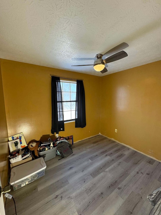 spare room with ceiling fan, a textured ceiling, and hardwood / wood-style flooring