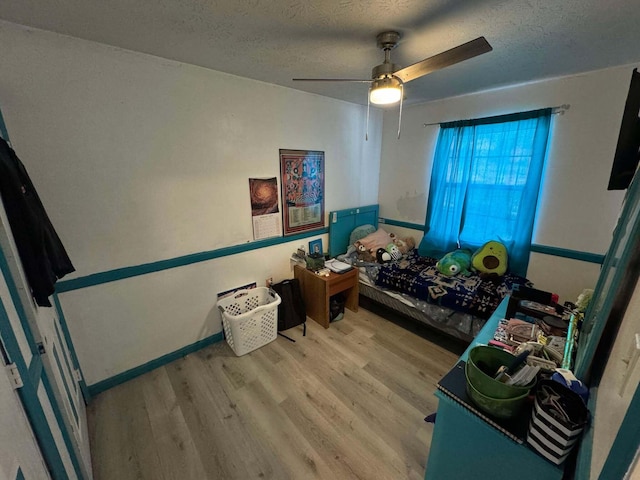 bedroom with ceiling fan, wood-type flooring, and a textured ceiling