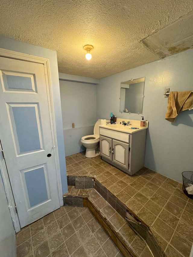 bathroom with vanity, a textured ceiling, and toilet