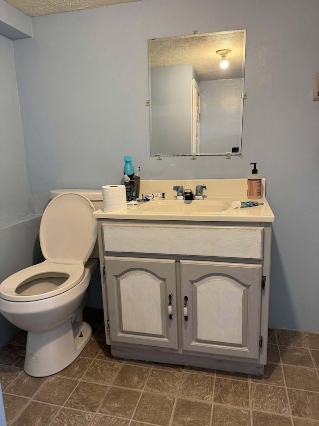 bathroom with vanity, a textured ceiling, and toilet