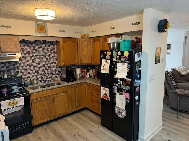 kitchen with light wood-type flooring, sink, tasteful backsplash, and black appliances