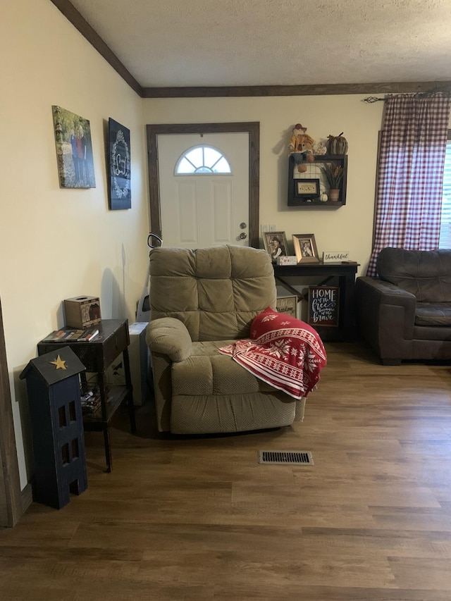 living room featuring a textured ceiling, hardwood / wood-style flooring, and crown molding