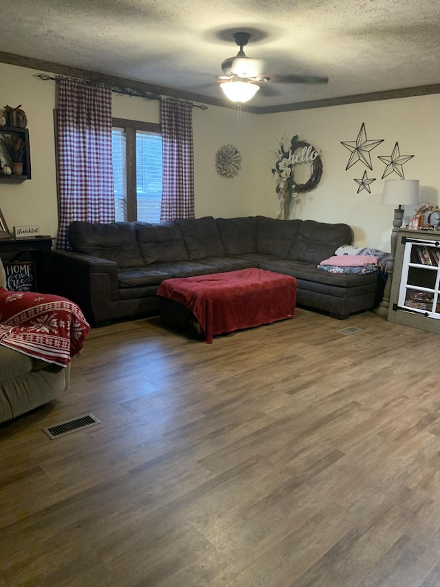 living room with a textured ceiling, ceiling fan, and hardwood / wood-style flooring