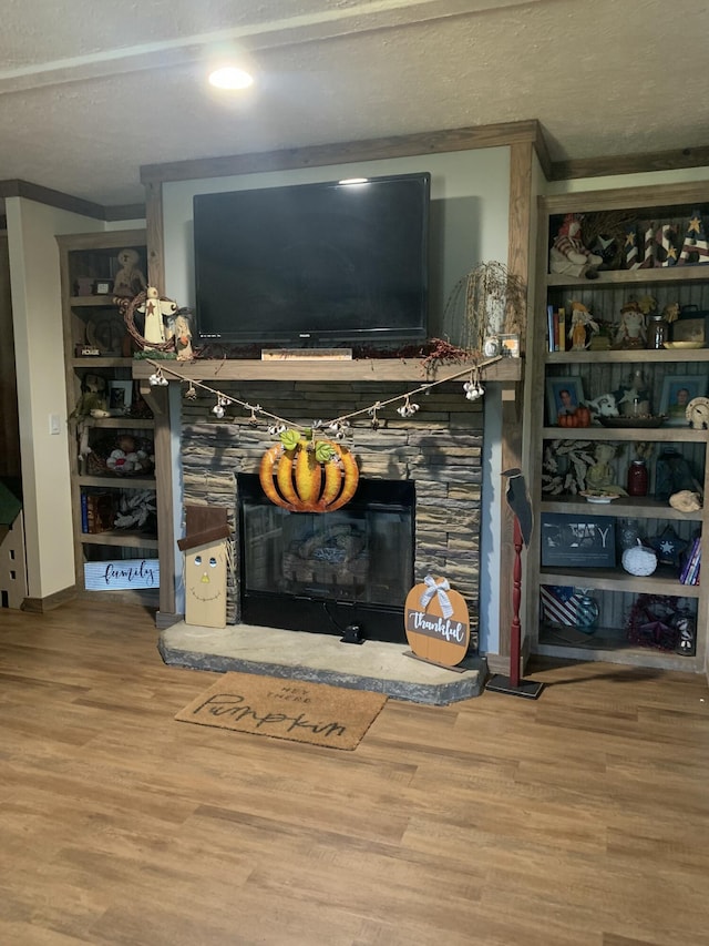 living room featuring wood-type flooring, a fireplace, ornamental molding, and a textured ceiling