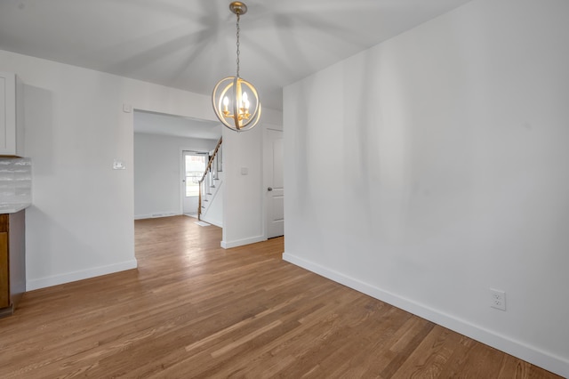 unfurnished dining area with hardwood / wood-style flooring and an inviting chandelier