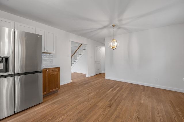 kitchen with white cabinetry, stainless steel fridge with ice dispenser, a notable chandelier, pendant lighting, and decorative backsplash