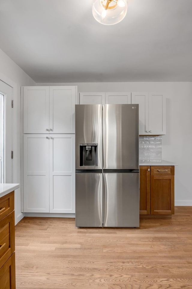 kitchen featuring stainless steel fridge with ice dispenser, tasteful backsplash, and white cabinetry