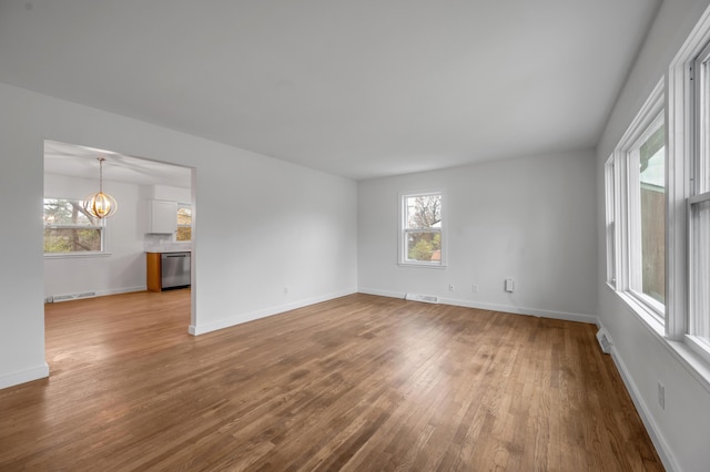 spare room featuring a notable chandelier and light hardwood / wood-style flooring