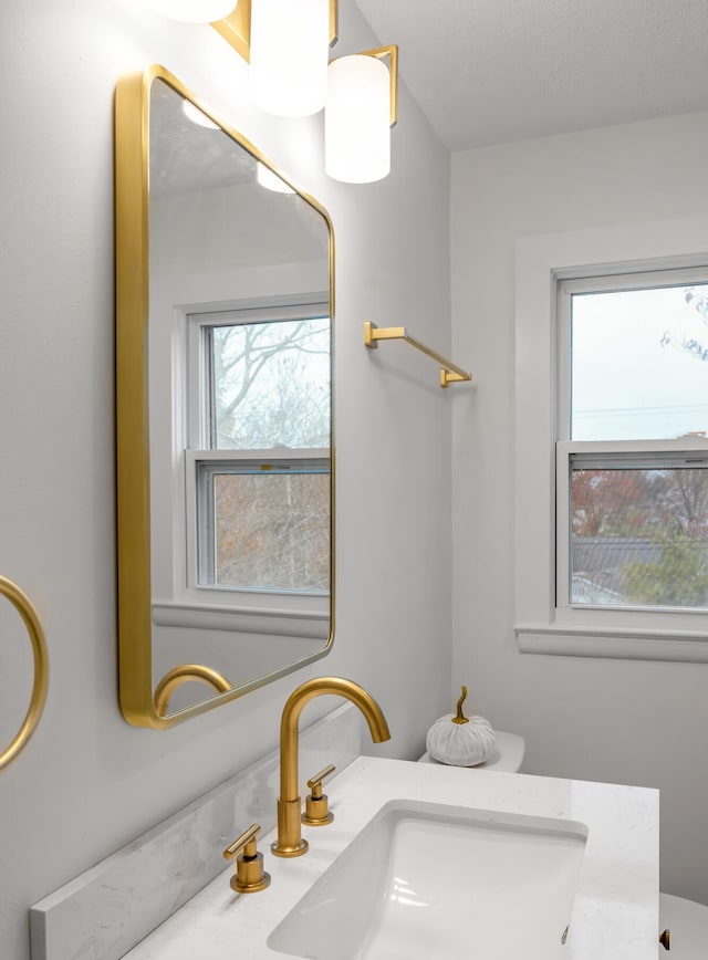 bathroom featuring vanity, a healthy amount of sunlight, and toilet