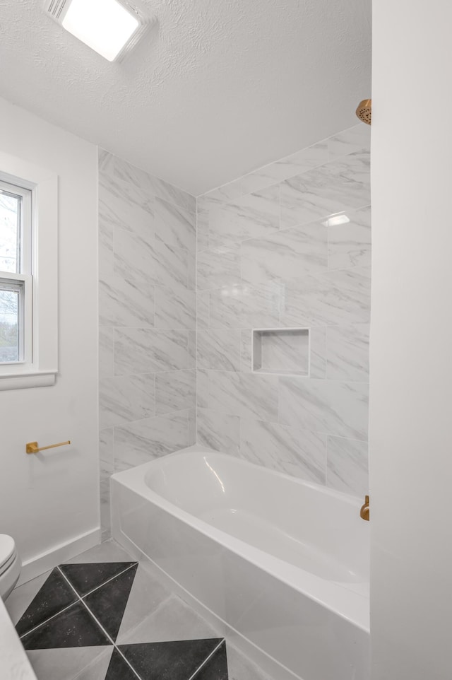 bathroom with tile patterned flooring, a textured ceiling, bathing tub / shower combination, and toilet