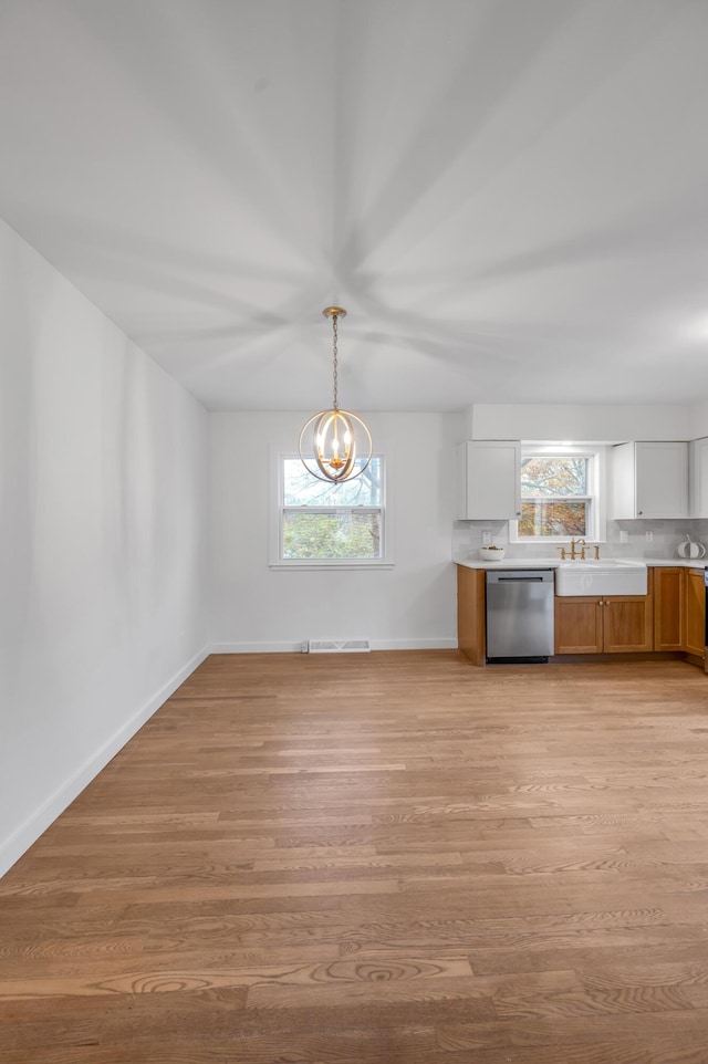 kitchen with white cabinets, pendant lighting, stainless steel dishwasher, and light wood-type flooring