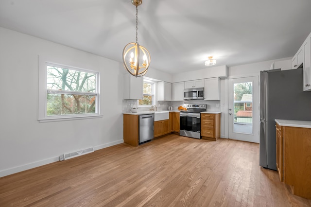 kitchen with white cabinets, decorative light fixtures, sink, and appliances with stainless steel finishes