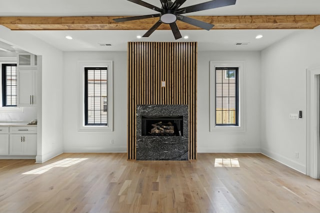 unfurnished living room featuring beamed ceiling, light hardwood / wood-style flooring, and ceiling fan