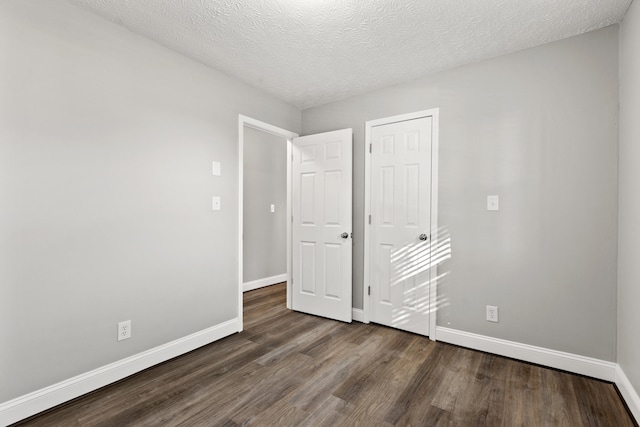 spare room with a textured ceiling and dark hardwood / wood-style flooring