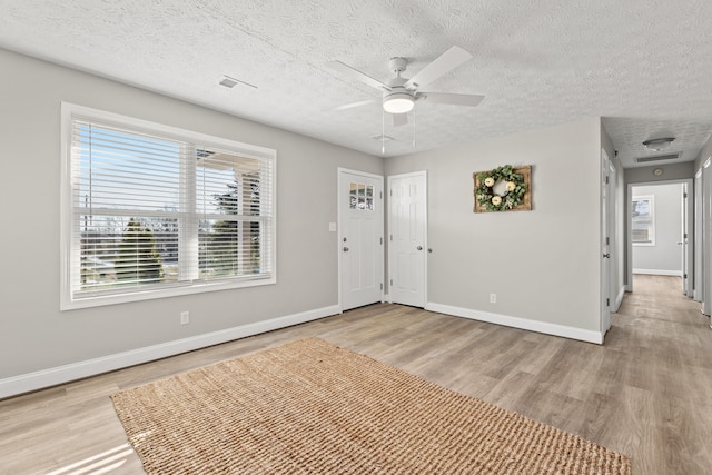 foyer entrance with ceiling fan, light wood-type flooring, and a textured ceiling