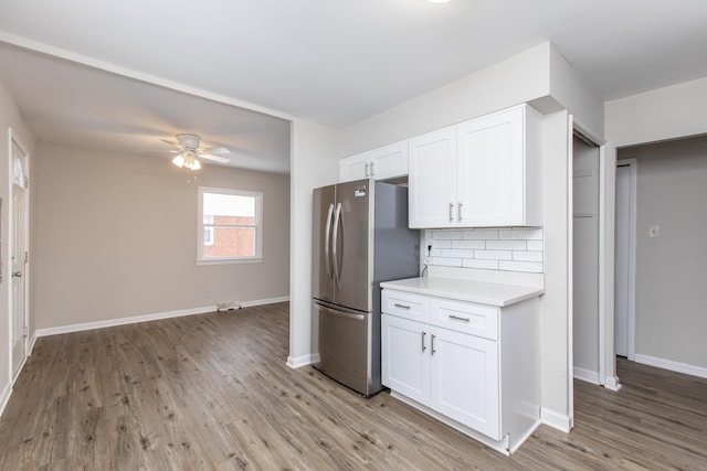 kitchen with stainless steel refrigerator, white cabinetry, ceiling fan, light hardwood / wood-style flooring, and backsplash