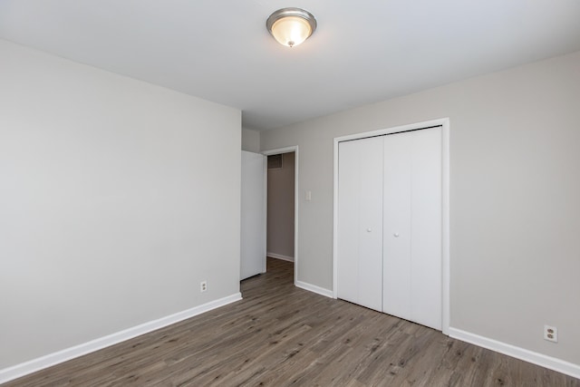 unfurnished bedroom with dark wood-type flooring and a closet