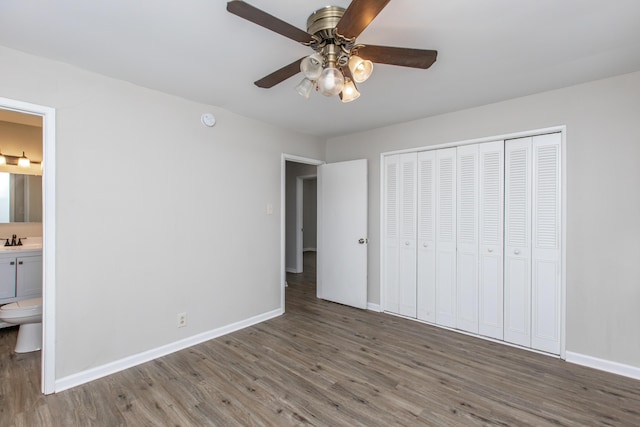 unfurnished bedroom featuring connected bathroom, ceiling fan, sink, dark hardwood / wood-style flooring, and a closet