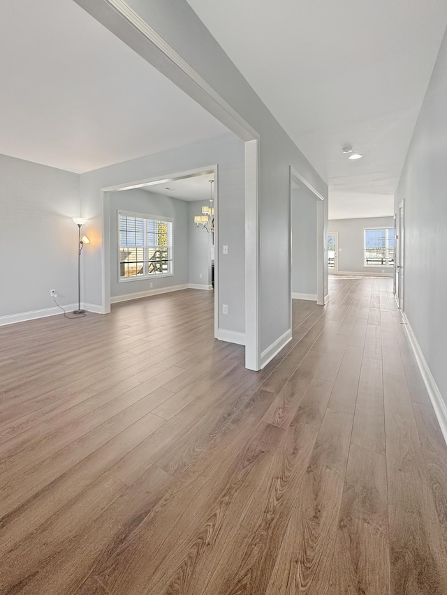 spare room with plenty of natural light, light hardwood / wood-style floors, and an inviting chandelier