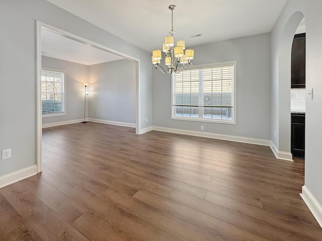 unfurnished dining area featuring dark hardwood / wood-style flooring, a chandelier, and a wealth of natural light