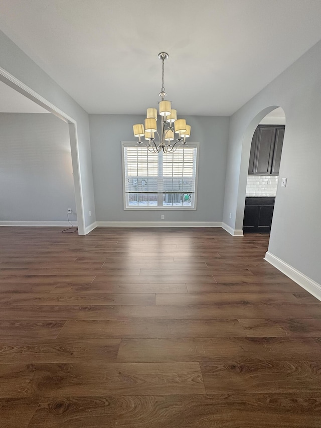 unfurnished dining area featuring a notable chandelier and dark hardwood / wood-style floors