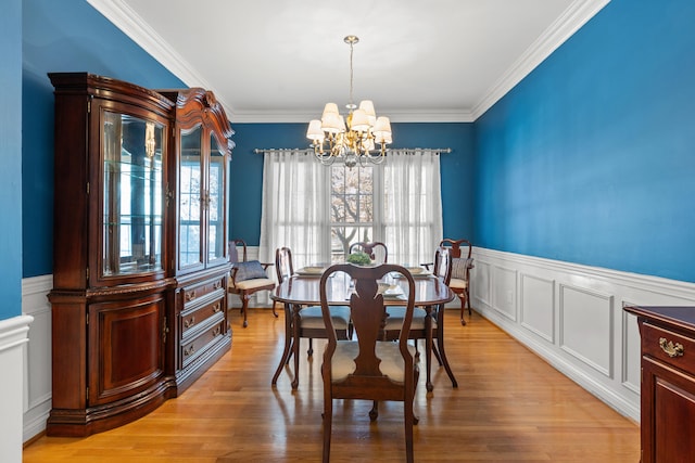 dining area featuring crown molding, light wood-type flooring, and an inviting chandelier