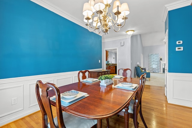 dining area featuring crown molding, a notable chandelier, and light wood-type flooring