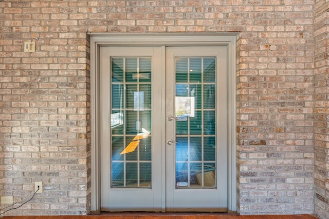 doorway to outside featuring french doors and brick wall