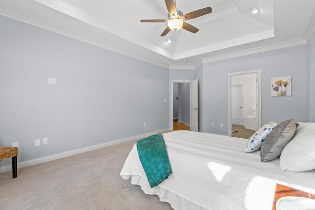 carpeted bedroom featuring ornamental molding, connected bathroom, ceiling fan, and a tray ceiling