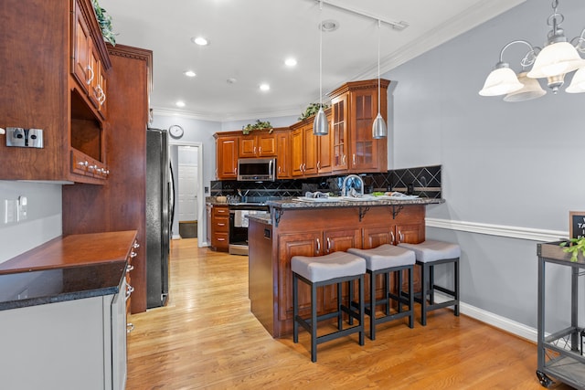 kitchen with a breakfast bar area, hanging light fixtures, appliances with stainless steel finishes, kitchen peninsula, and backsplash