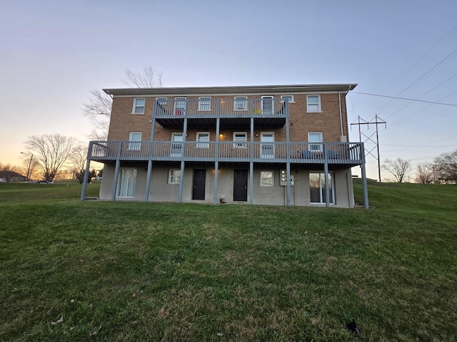 back house at dusk with a wooden deck and a lawn